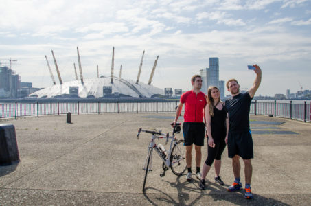 Group of cyclists taking a selfie with the O2 in the background