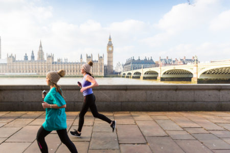 Two female runners running along the banks of the Thames opposite the Houses of Parliament