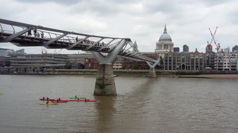 Londoners walking on Millenium Bridge with Tate Modern in the background