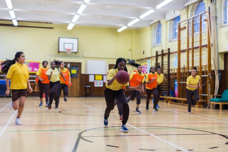 Young girls playing basketball in an indoor location