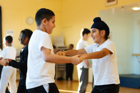 Two young children dancing in PE Kit in school