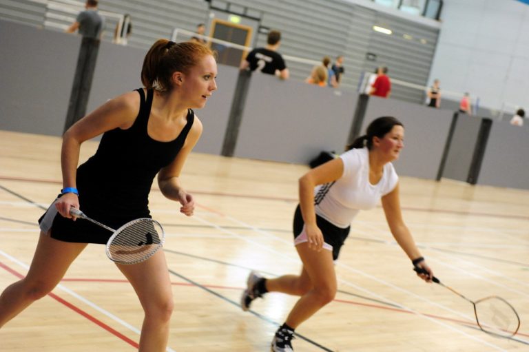 Two girls playing badminton indoors