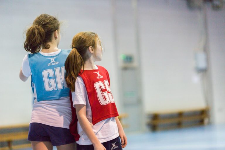 Two young girls playing netball in sports hall