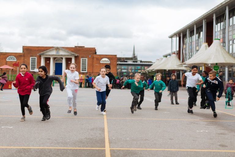 Group of primary school children running on a school's outdoor court