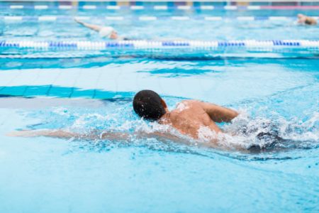 A man swims lengths in an empty swimming pool