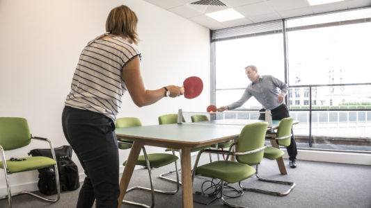 Two employees playing table tennis for workplace physical activity