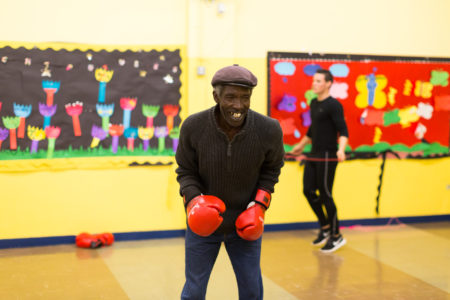 Older man wearing boxing gloves in indoor gym