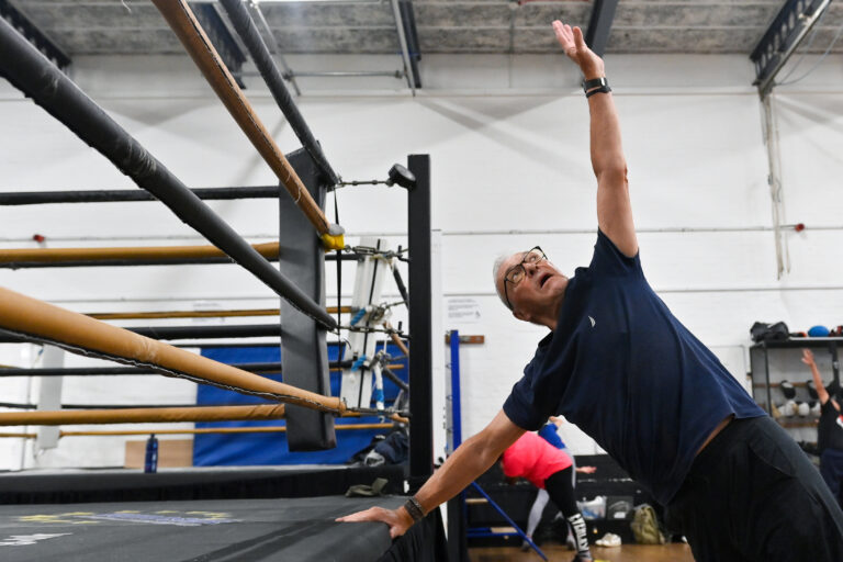 Man stretching next to boxing ring.