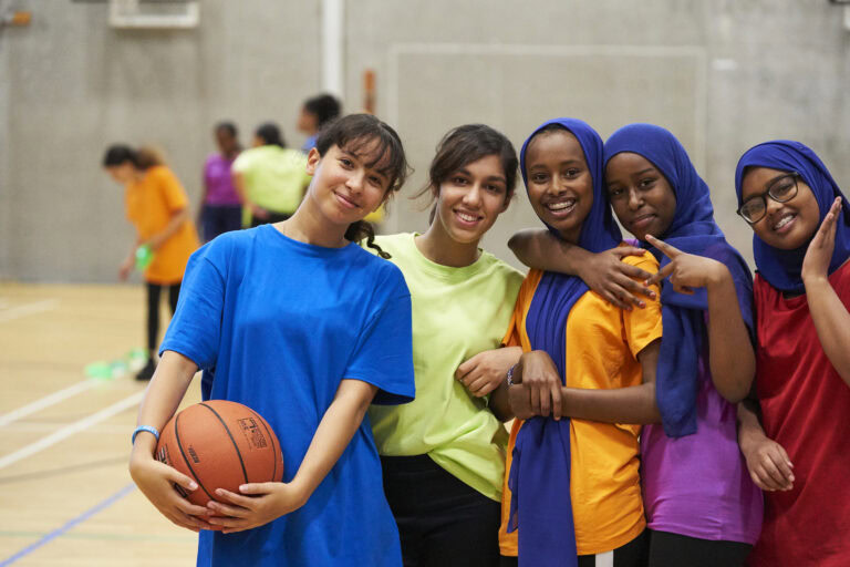 Girls posing for photo whilst playing basketball